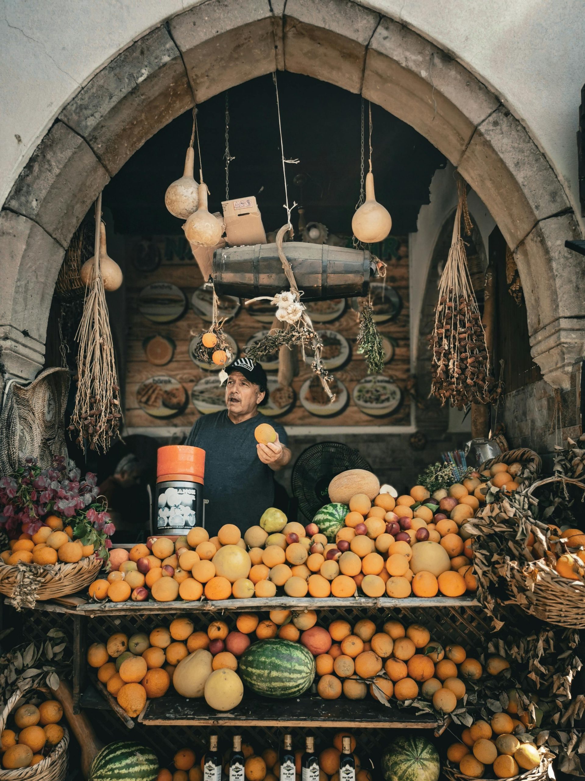 Man selling fresh fruits at a vibrant market stall with hanging decorations.