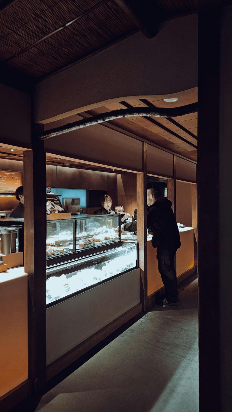 Warmly lit bakery with people choosing delicious pastries on display.
